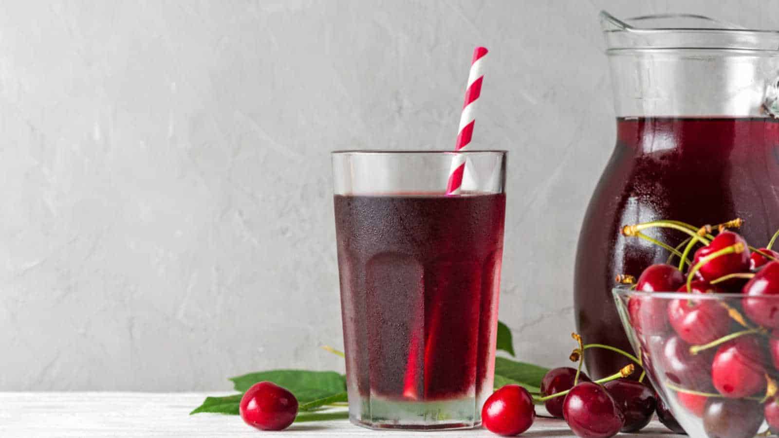 Cold cherry juice in a glass with a straw and jug