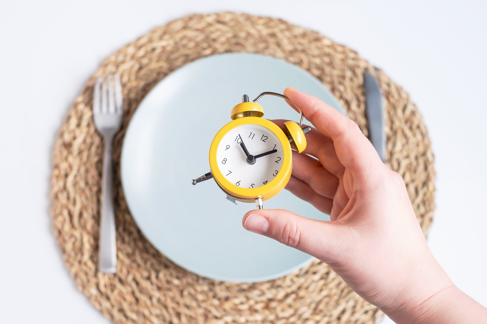 “empty plate with fork and knife and wall clock in background