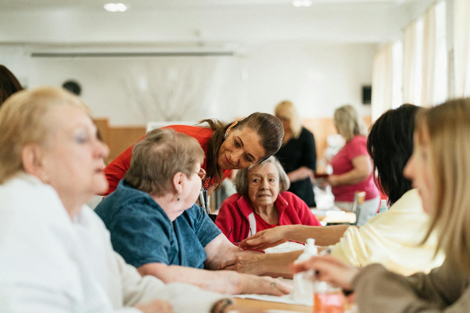 Smiling caregivers and seniors engage over a table at a community center. Social Support Systems