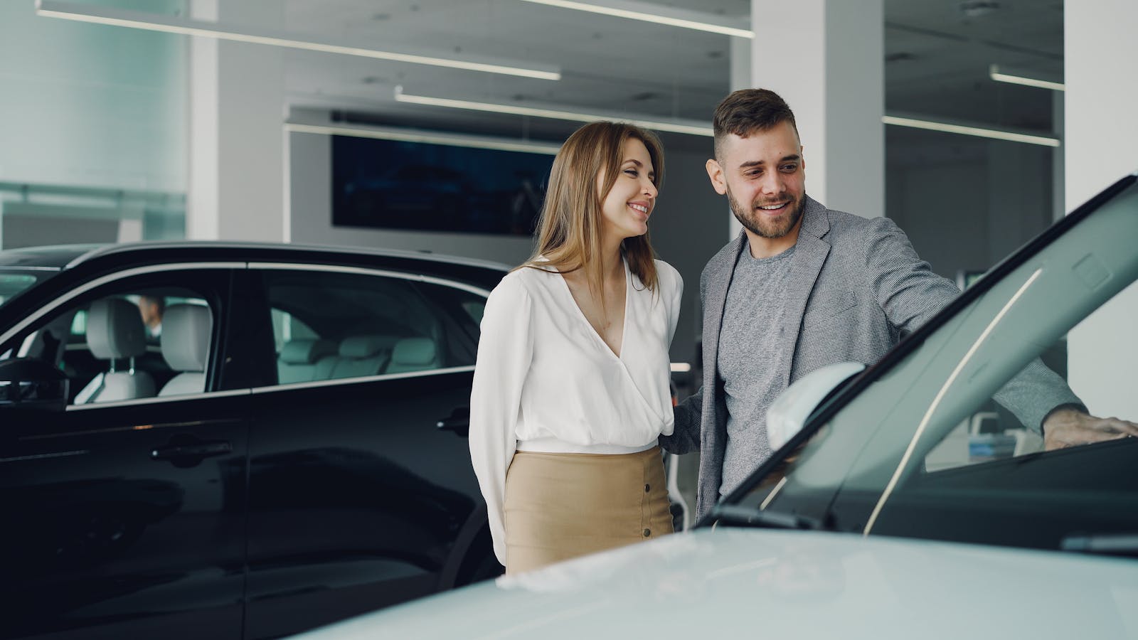 Smiling couple exploring cars at dealership, enjoying shopping experience. New Vehicle