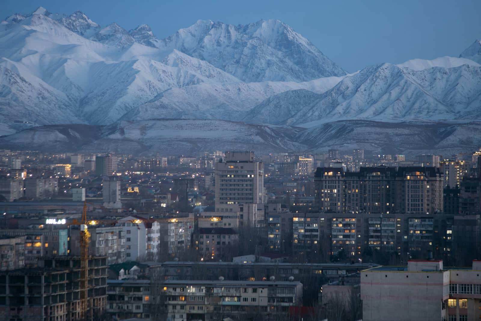 Stunning aerial view of Bishkek city. Kyrgyzstan against a backdrop of snow-covered mountains during twilight.