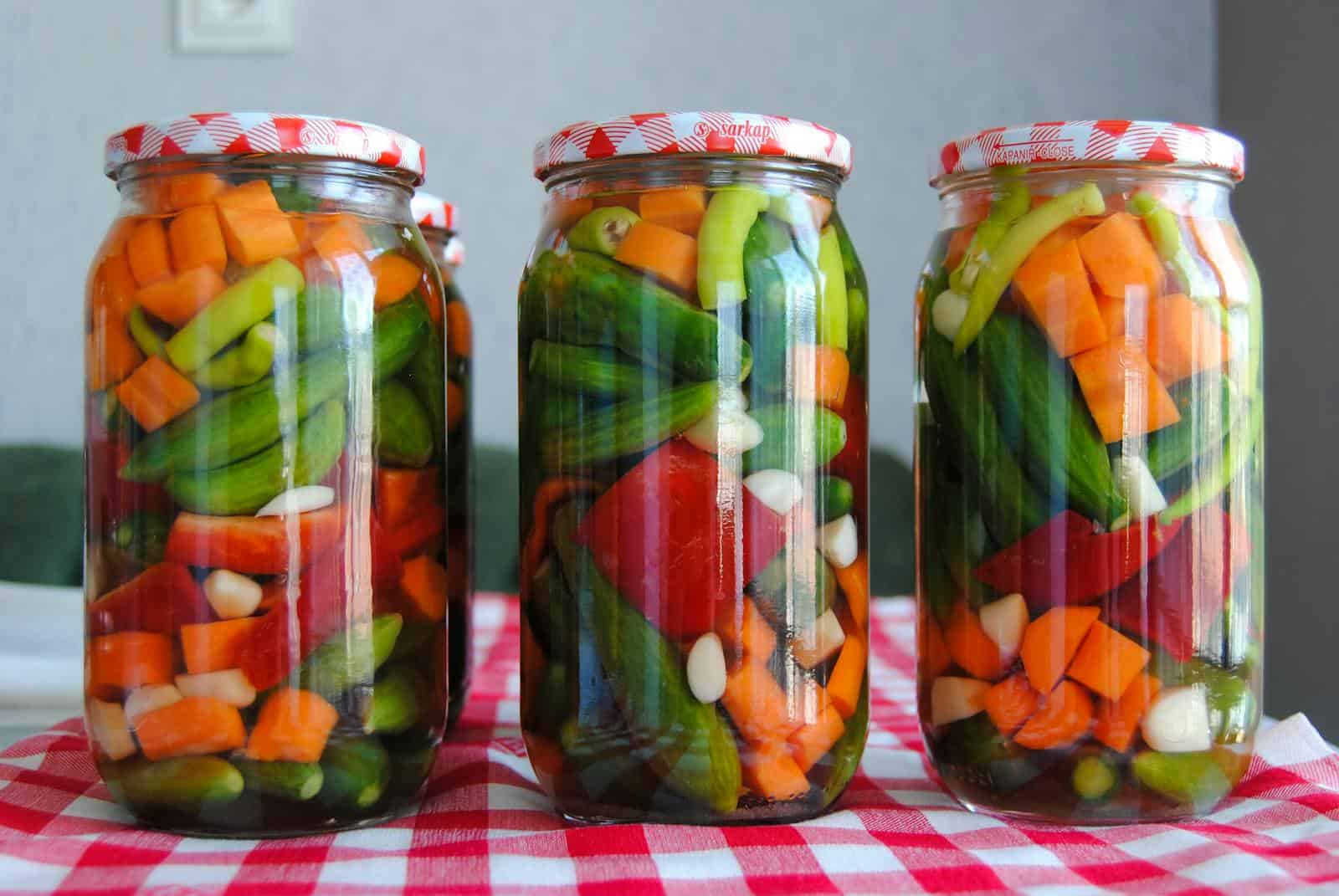 Three jars of assorted pickled vegetables on a red checkered tablecloth. Canned Vegetables