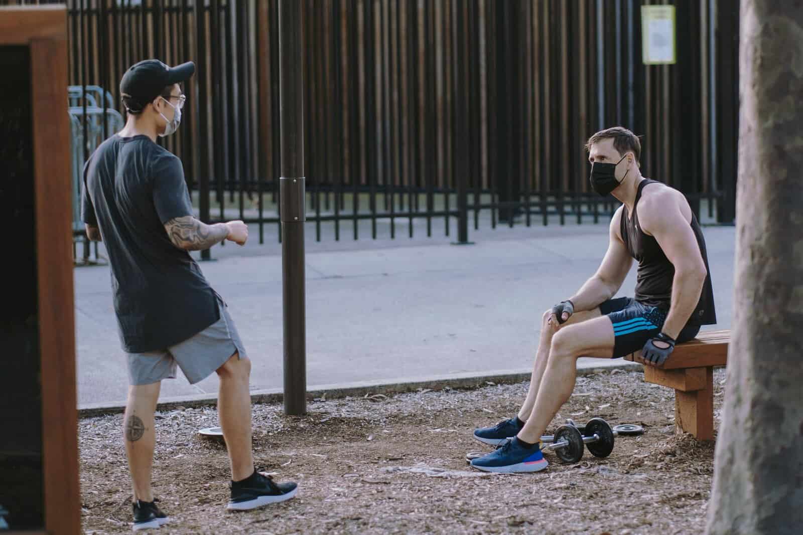 Two men exercising with face masks in Sydney park, practicing social distancing.