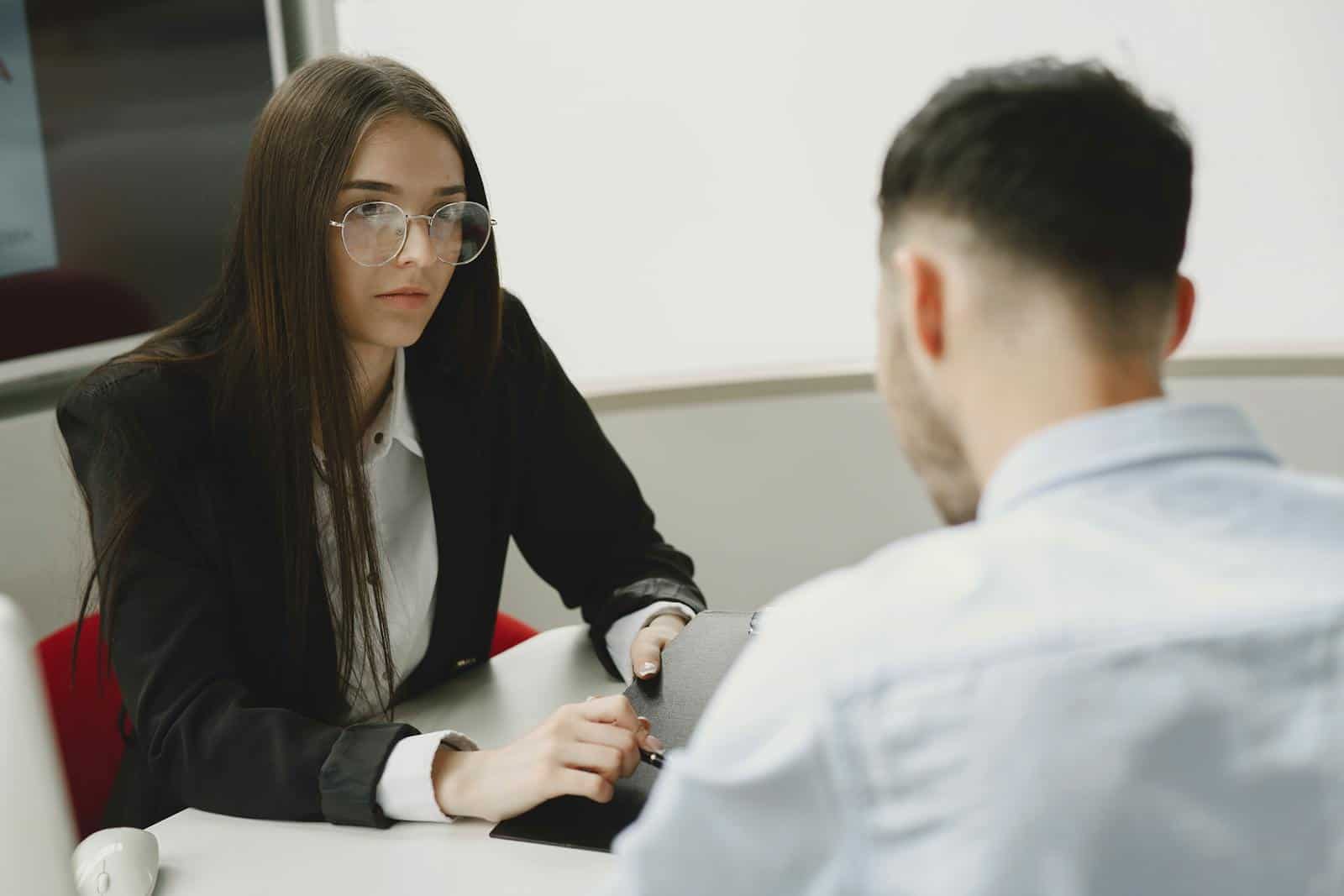 Two professionals engage in a serious business meeting at a modern office setting.