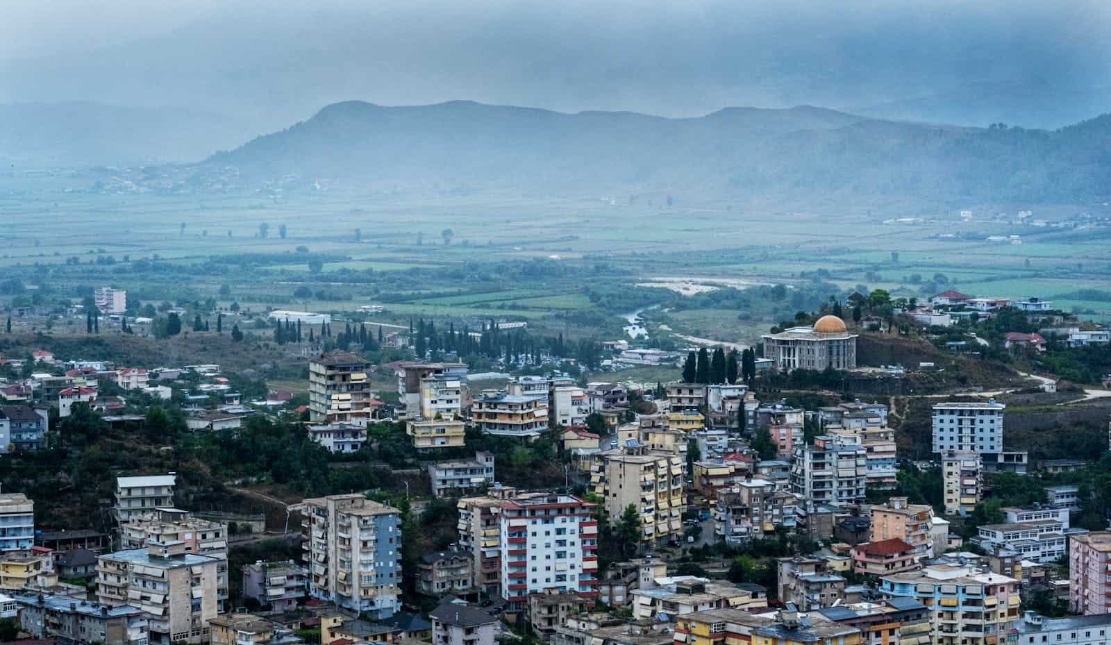 Vibrant cityscape of Albania with lush greenery and mountainous backdrop.