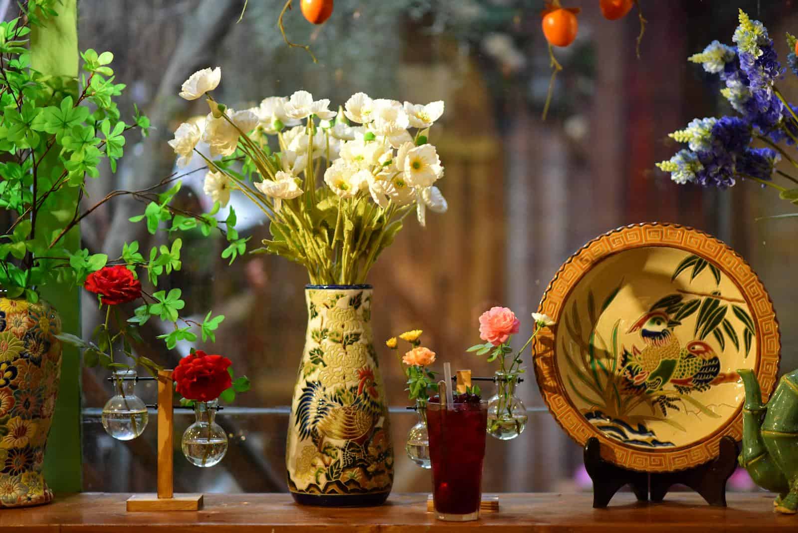 Beautiful floral arrangement with colorful vases and patterned plate. Perfect for interior decor inspiration.