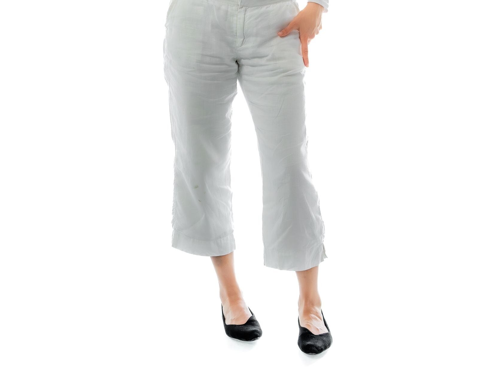 Elegant woman in white outfit poses artistically against white background, showcasing grace and style.