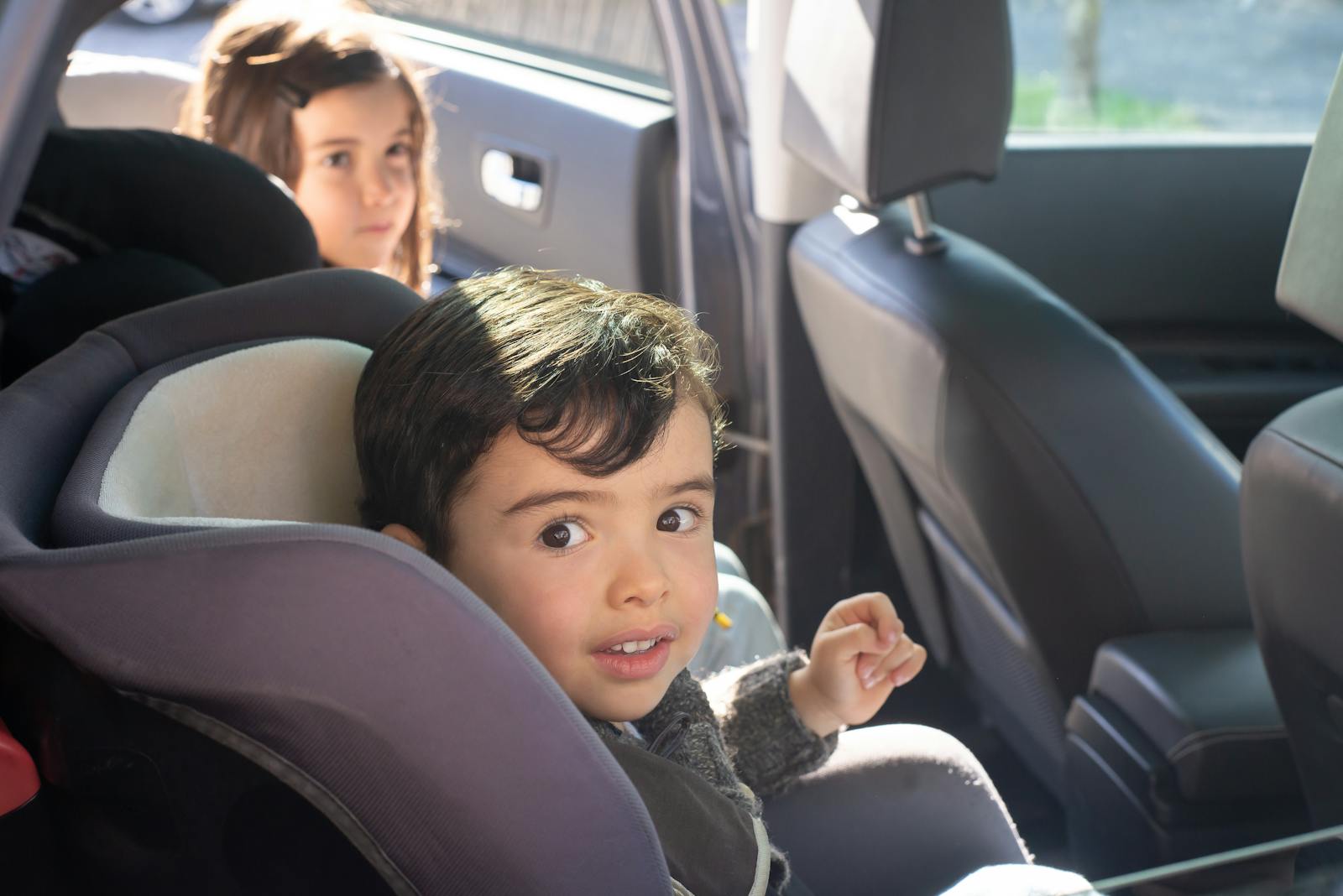 Two children sitting in a car, enjoying a family ride in Portugal. car seat