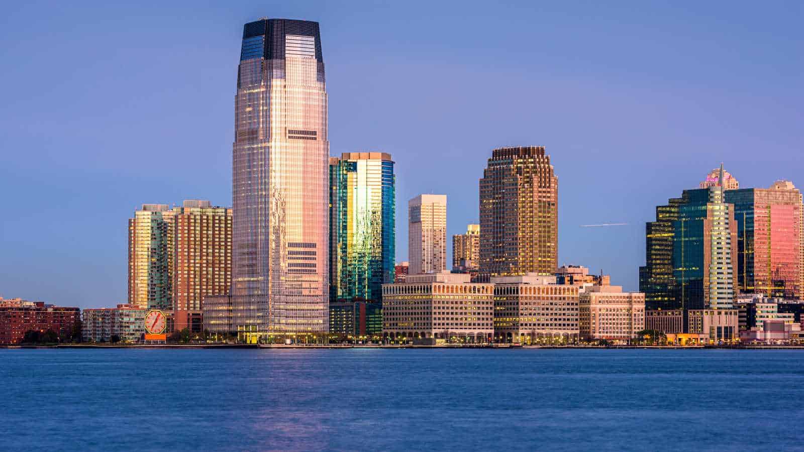 City skyline with tall skyscrapers reflected in the water at sunset.