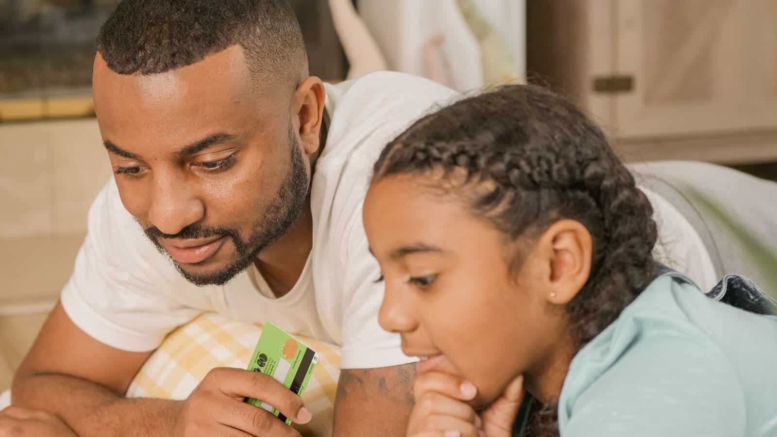 A father and daughter bonding while making an online purchase at home.