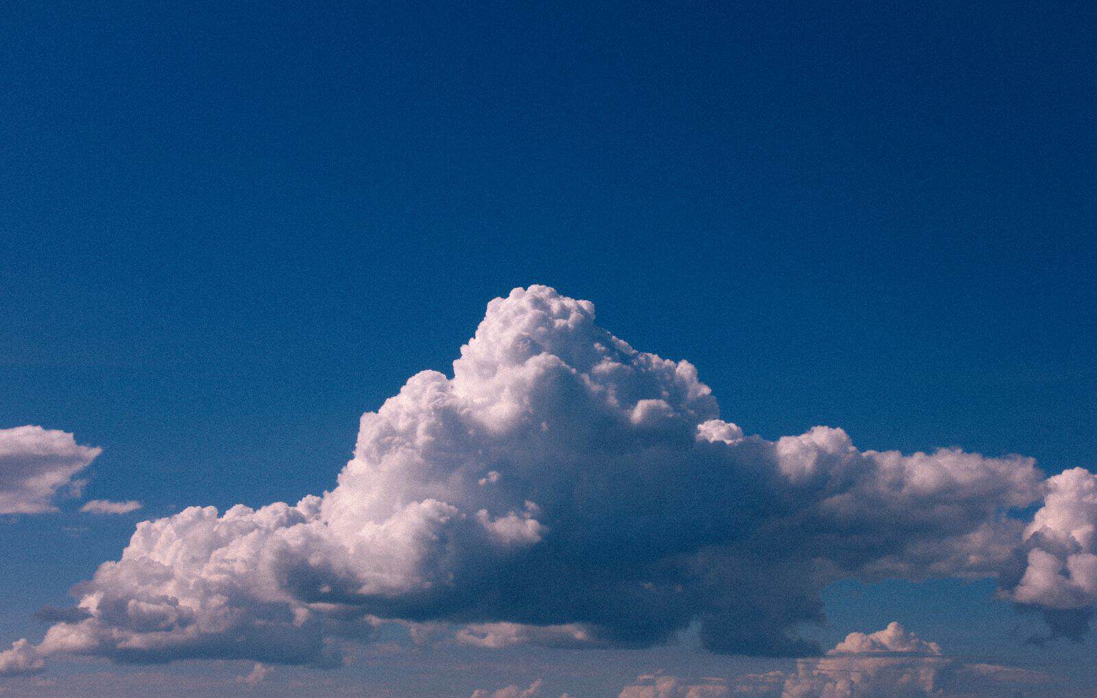 A peaceful view of cumulus clouds against a deep blue sky, captured at day.