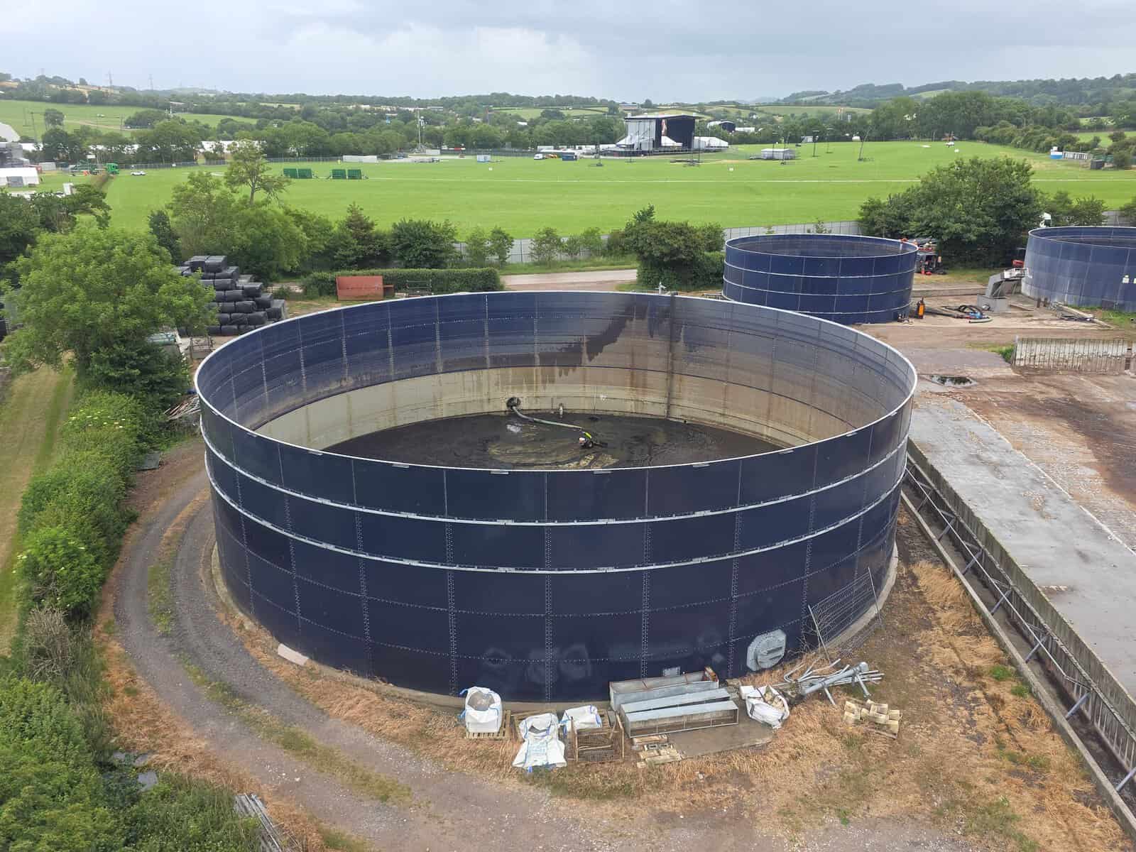 Aerial photo showcasing large industrial water tanks amidst lush countryside landscape under cloudy sky.