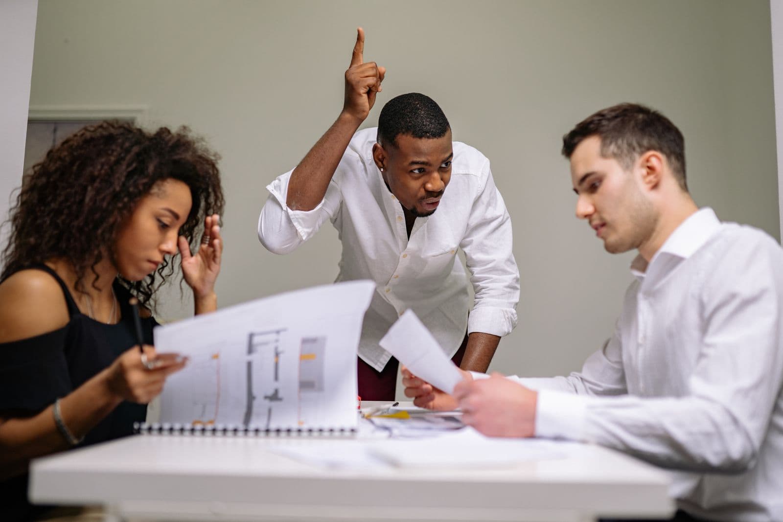 Business professionals engaged in intense discussion over documents in a meeting room.