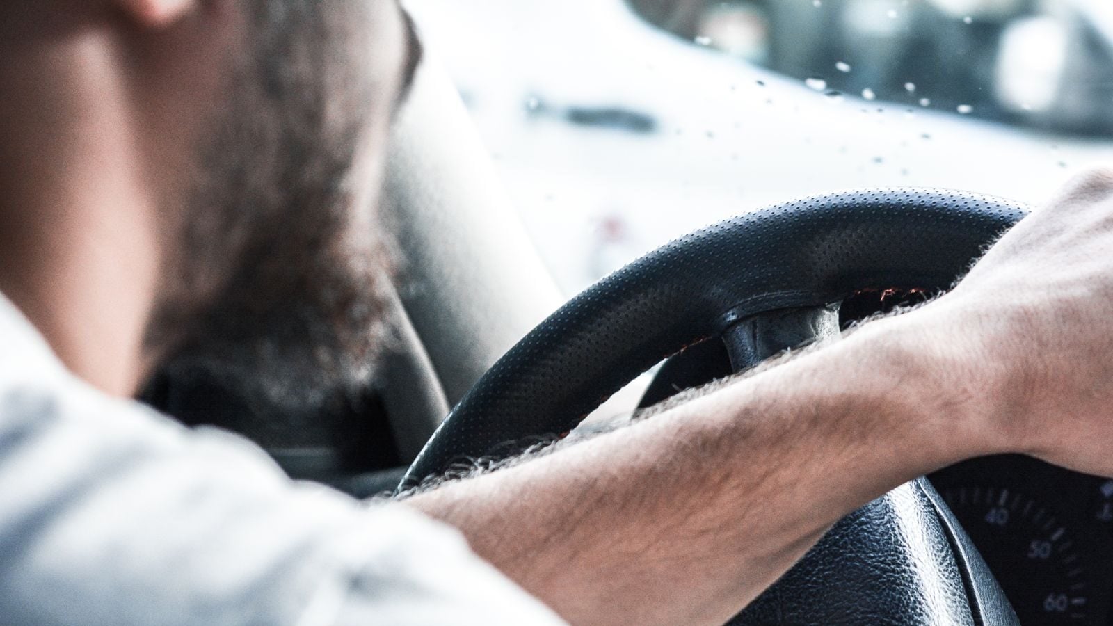 Man gripping Volkswagen steering wheel, focused on driving and vehicle interior details.