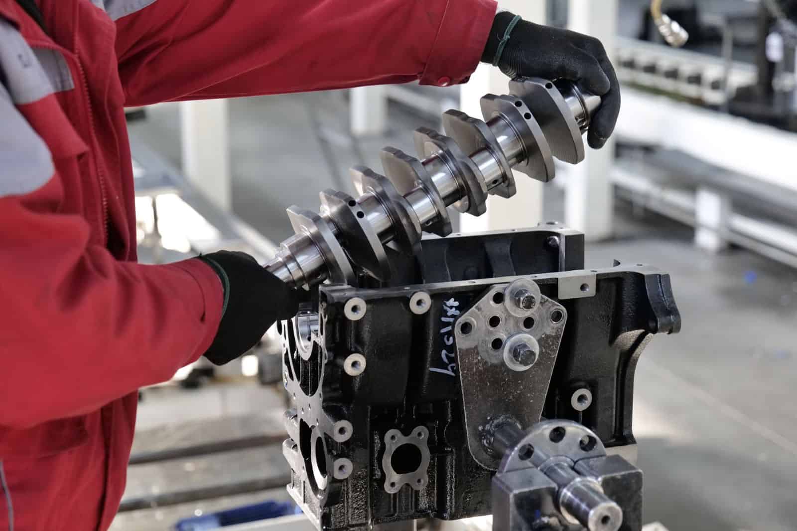 Mechanic working on a crankshaft installation in an engine block in an industrial setting. Automobile